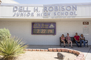 people sitting on a bench in front of dell h robison jr high school